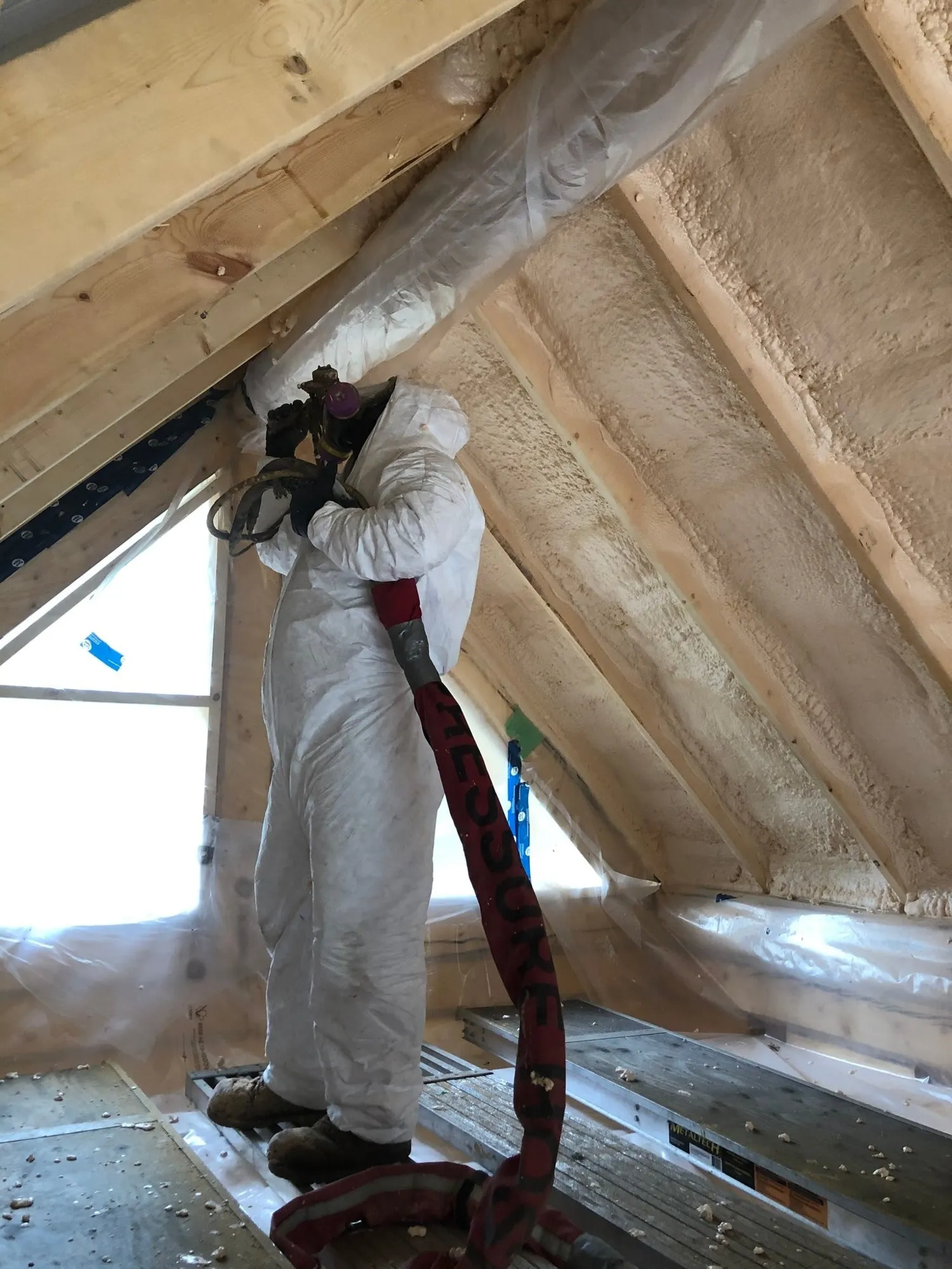 Spray foam installer applying insulation