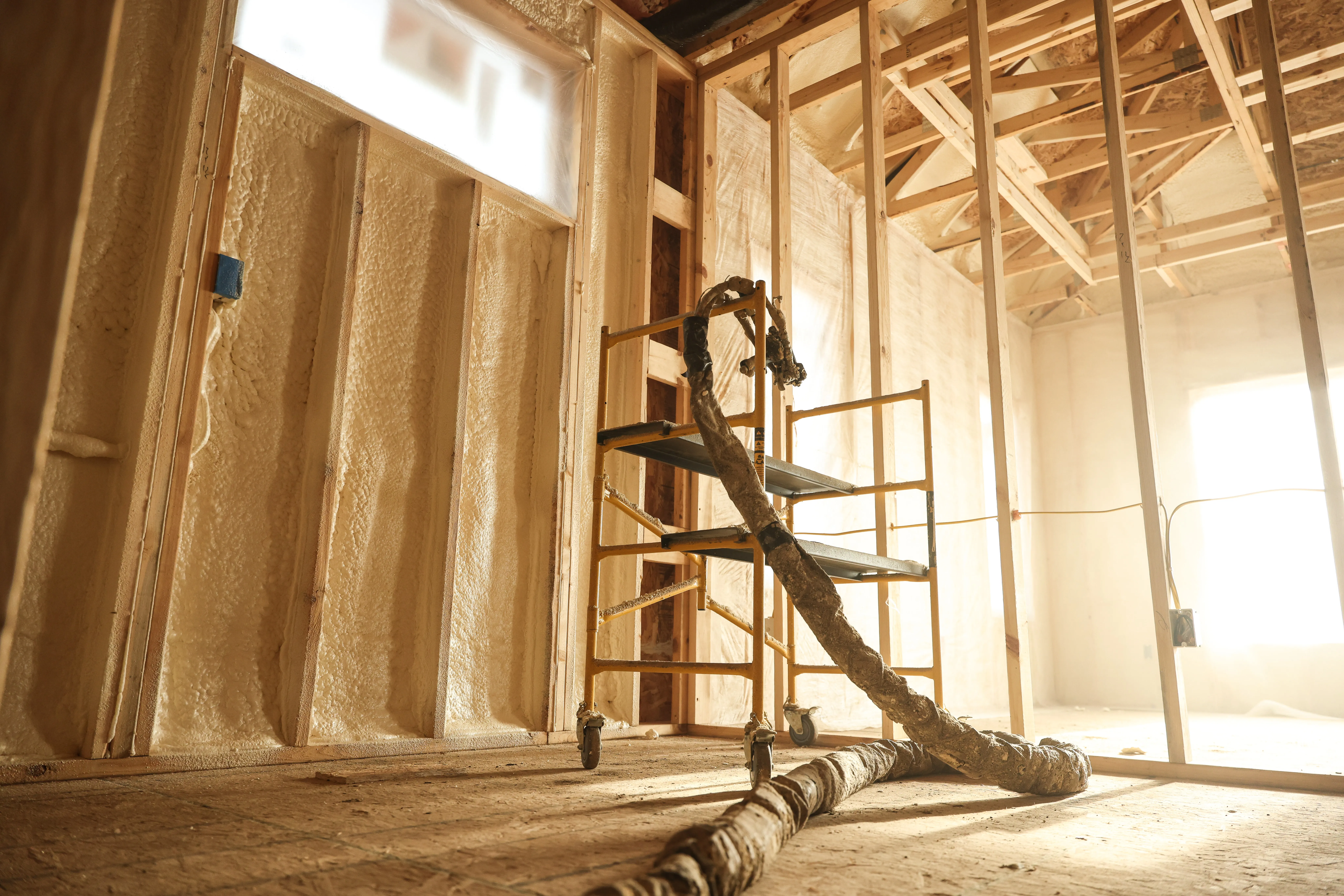 Installer applying spray foam between framing